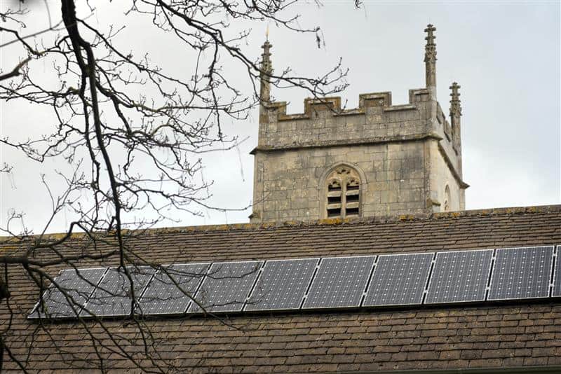 Solar panels on a church roof with the tower in the background